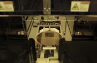 Wafer de silício sendo processado por máquina automatizada de fabricação de semicondutores.