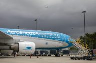 Avião Aerolíneas Argentinas Airbus A330-200 no pátio do aeroporto sob céu nublado. Outro avião menor no céu.