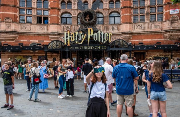 Multidão na entrada do edifício Harry Potter, com o letreiro "Harry Potter" em destaque.