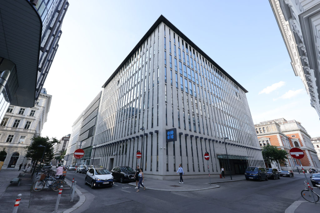 Edifício moderno da OPEP, com fachada vertical, em um cruzamento de rua movimentado com pessoas e veículos em Viena.