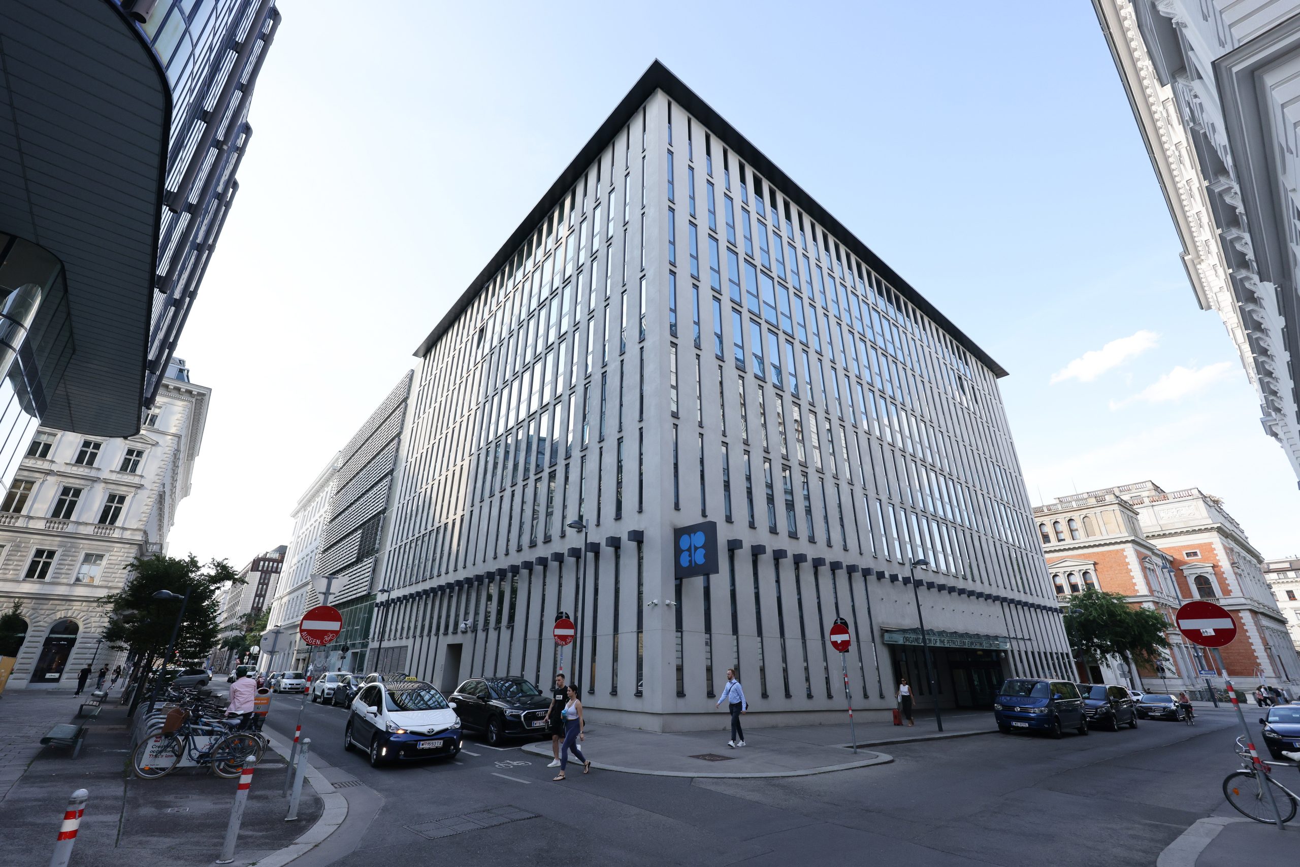 Edifício moderno da OPEP, com fachada vertical, em um cruzamento de rua movimentado com pessoas e veículos em Viena.