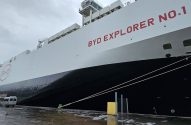 Navio BYD EXPLORER NO. 1, com logo BYD, atracado em porto com chão molhado e vans próximas.
