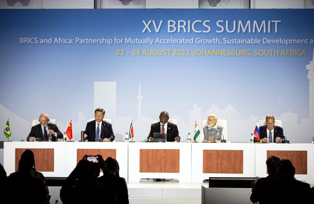 XV Cúpula do BRICS em Joanesburgo, 2023. Líderes sentados à mesa com suas bandeiras nacionais.