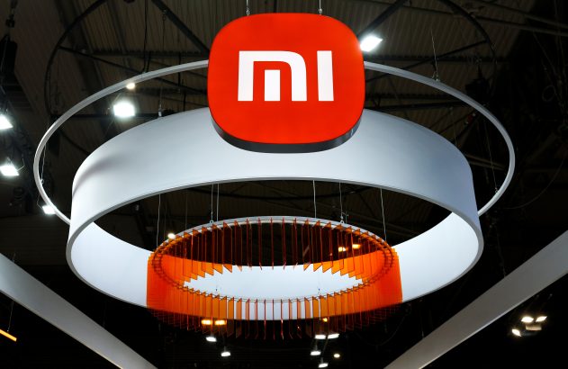 Logotipo da Xiaomi (MI) vermelho e branco suspenso, com anéis brancos e um anel interno laranja.