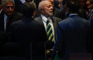 Presidente Lula, de terno e gravata listrada, conversa em grupo formal.
