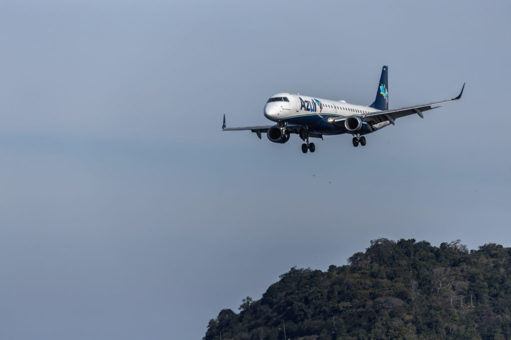 Avião da Azul em aproximação de pouso sobre montanhas. Céu cinzento.