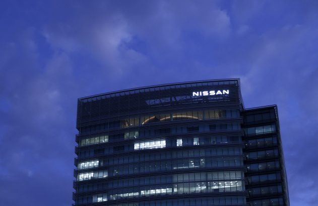 Edifício Nissan à noite, com logo e janelas iluminadas, sob céu azul escuro.