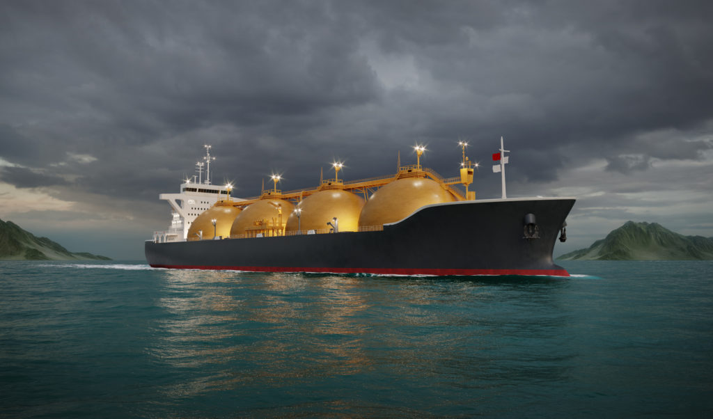 Navio gaseiro com tanques esféricos navegando no mar sob céu nublado e montanhas distantes.