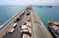 Porto de contêineres com navio cargueiro atracado. Pilhas de contêineres na doca e mar azul.