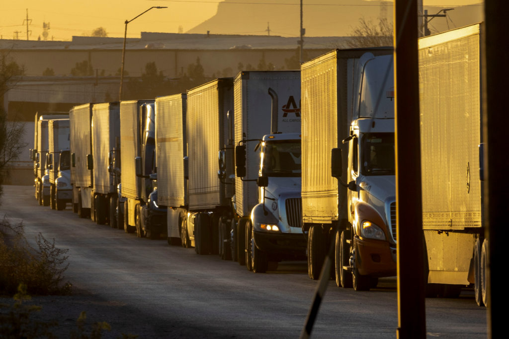 Longa fila de caminhões parados em uma rodovia.