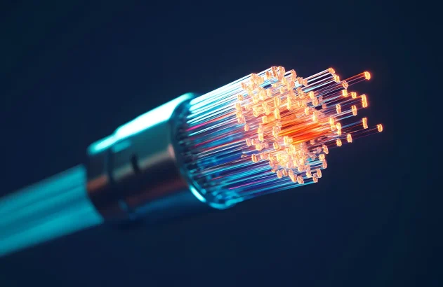 Um cabo de fibra óptica com fibras brilhantes em tons de laranja, vermelho e azul destaca-se contra um fundo escuro, transmitindo tecnologia avançada e comunicação.