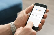 Mãos de um homem segurando um celular na página do Google