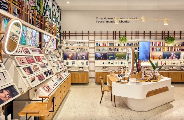 Imagem de uma loja da Natura, marca de cosméticos, moderna e bem iluminada com prateleiras cheias de produtos de maquiagem, perfumes e cosméticos para homens, e uma ilha central com design sofisticado.
