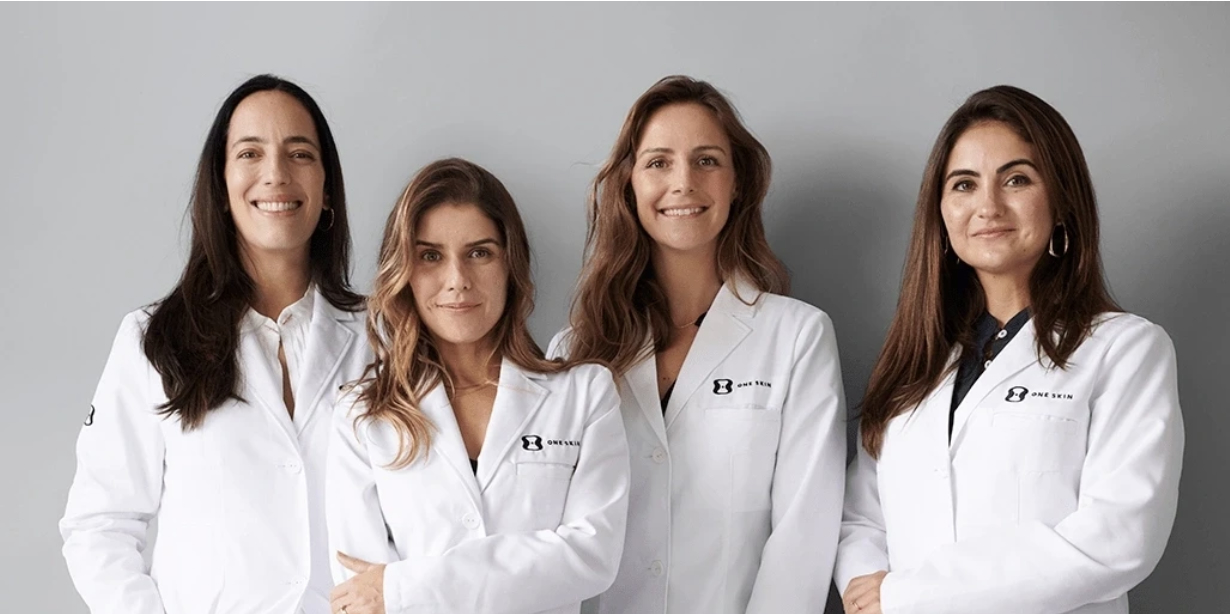 Quatro mulheres sorrindo, usando jalecos brancos.