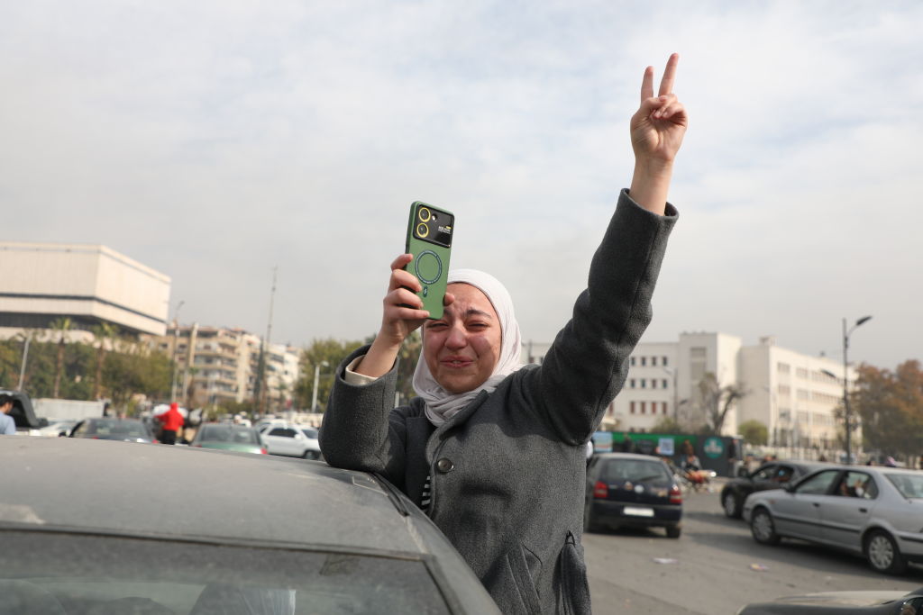 Mulher comemora na rua em Damasco, na Síria, após a notícia de que Bashar al-Assad fugiu do país e renunciou à presidência