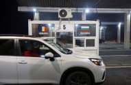 Carro branco com duas pessoas em guarita de fronteira entre Romênia e Bulgária, com o número "5", à noite.