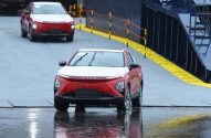 Carros vermelhos OMODA em rampa molhada. Um em destaque com limpadores levantados, outro carro ao fundo.