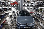 Um Volkswagen cinza à frente, com dezenas de carros em uma torre de armazenamento automotiva robótica na Autostadt.