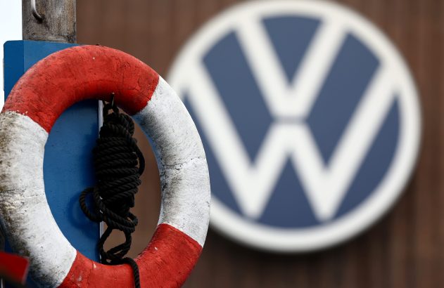 Boia salva-vidas vermelha e branca em primeiro plano. Ao fundo, logo desfocado da Volkswagen (VW).