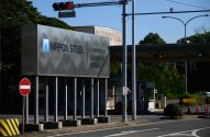 Portaria da NIPPON STEEL com letreiro da empresa, semáforo vermelho e placa de sentido proibido.