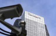 Prédio da Tencent com câmera de segurança desfocada em primeiro plano contra céu azul.