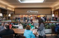 Pessoas em um shopping, com a loja JCPenney ao fundo exibindo ofertas de Black Friday.