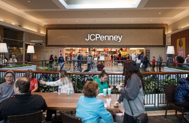 Pessoas em um shopping, com a loja JCPenney ao fundo exibindo ofertas de Black Friday.