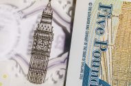 Nota de £5 britânica. Ilustração de Big Ben e texto "Five Pound". Detalhes translúcidos visíveis.