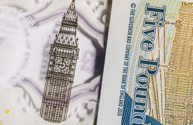 Nota de £5 britânica. Ilustração de Big Ben e texto "Five Pound". Detalhes translúcidos visíveis.