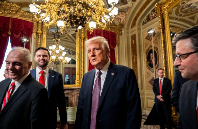 Donald Trump e outros homens em ternos formais caminham por uma sala opulenta com lustres e espelhos dourados.