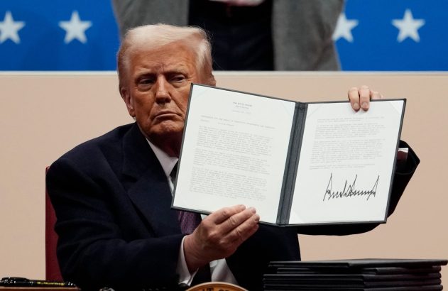 Donald Trump mostra memorando assinado sobre congelamento de contratações federais, com estrelas ao fundo.