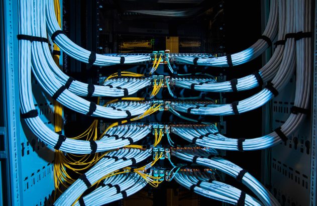 Cabos de rede brancos e amarelos, meticulosamente organizados em um rack de servidor de data center.