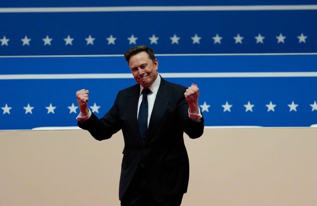 Elon Musk, de terno, comemora com punhos erguidos à frente de um fundo azul com listras e estrelas brancas.