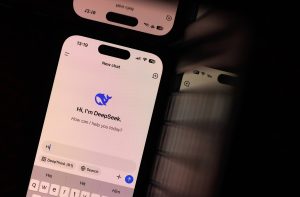 Celular exibe interface do chatbot DeepSeek com saudação e usuário digitando 'Hi' no teclado.