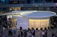 Loja Louis Vuitton iluminada em Sanlitun, com teto circular e pessoas caminhando em movimentada área comercial ao anoitecer.
