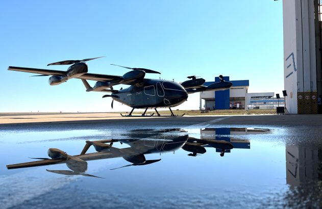 Aeronave eVTOL escura da Eve em pista com reflexo nítido em poça.