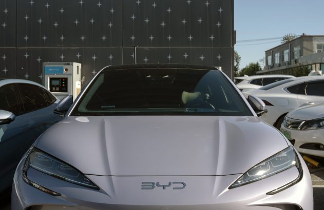 Braços robóticos montam veículos em uma linha de produção automotiva. Indústria moderna e automatizada.