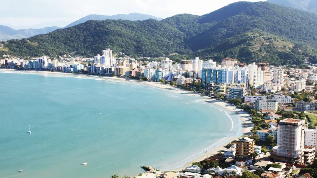 Enseada com água calma e prédios altos em colinas, proporcionando uma vista urbanizada.