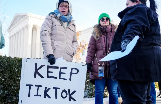 Um grupo de pessoas vestidas para o frio segura um cartaz "KEEP TIKTOK" em frente ao edifício da Suprema Corte dos EUA, sugerindo um protesto relacionado ao aplicativo TikTok.