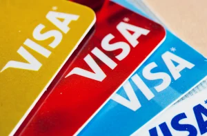 Conjunto sobreposto de quatro cartões Visa em dourado, vermelho, azul e branco, formando um padrão colorido e vibrante.