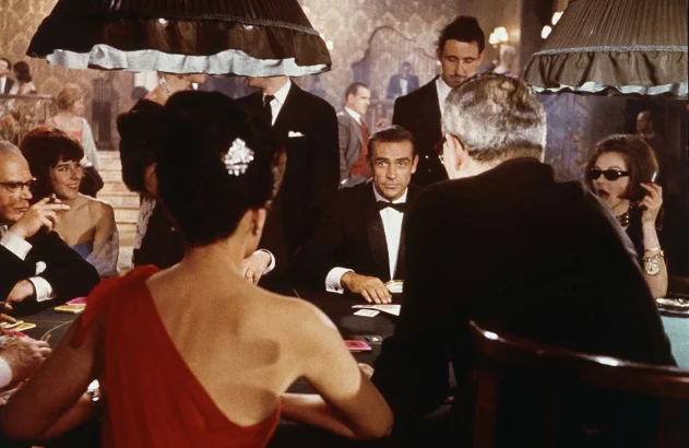Sean Connery, como o agente secreto James Bond, sentado em uma mesa de jogo de cassino em uma cena do filme 'Dr. No.'