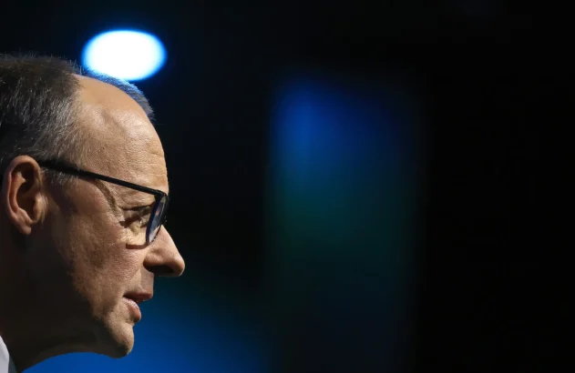 Close-up do perfil de um homem de óculos. Fundo escuro com iluminação azul e um círculo de luz branco.