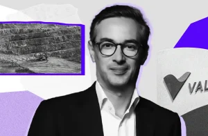 Executivo da Vale sorri, com mina de minério e logo ao fundo. Tema: mineração e indústria.