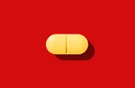 Imagem de um comprimido amarelo oblongo com linha de divisão sobre um fundo vermelho vibrante, com sombra projetada para a parte inferior direita.