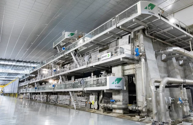 Complexa máquina de produção Klabin/Valmet domina o interior de uma fábrica industrial espaçosa e moderna.