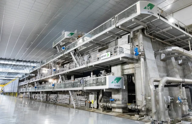 Complexa máquina de produção Klabin/Valmet domina o interior de uma fábrica industrial espaçosa e moderna.