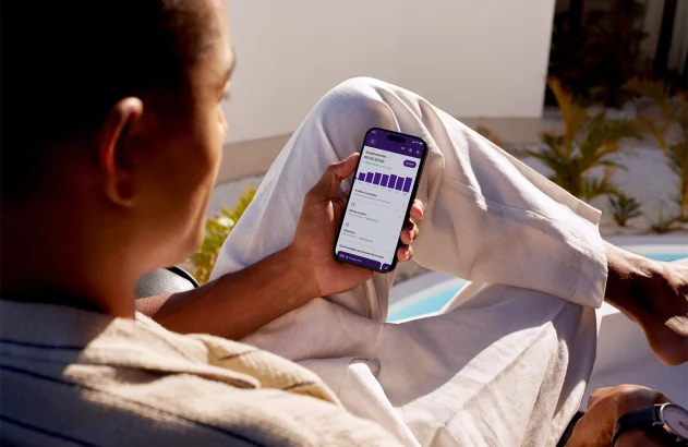 Pessoa olhando app de investimentos em smartphone, ao ar livre.