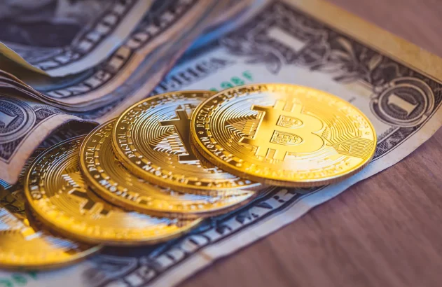 Moedas Bitcoin douradas sobre notas de dólar americano.