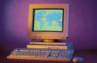 Imagem de um computador retro, com monitor CRT exibindo um mapa-múndi interconectado, em fundo roxo nostálgico.