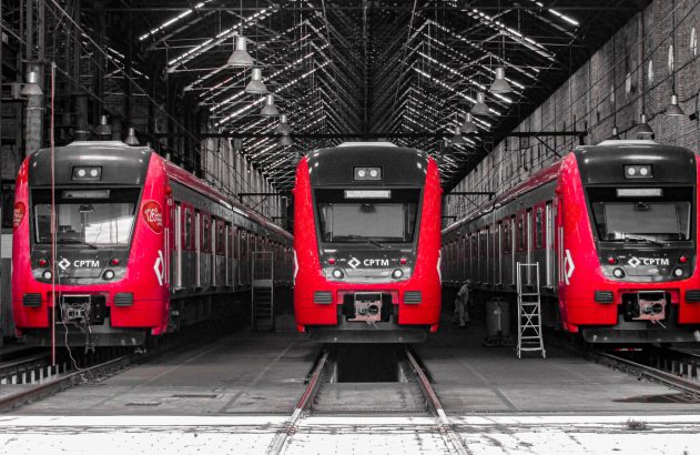 Três trens vermelhos e pretos CPTM alinhados em depósito ferroviário, fundo em P&B.